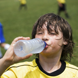 Boy drinking from a bottle of cold water during a football match