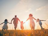 A happy family skipping through a field at sunset