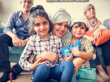 A Muslim family sitting on and around the sofa in their living room