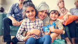 A Muslim family sitting on and around the sofa in their living room