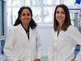 An image of two female scientists in lab coats, smiling